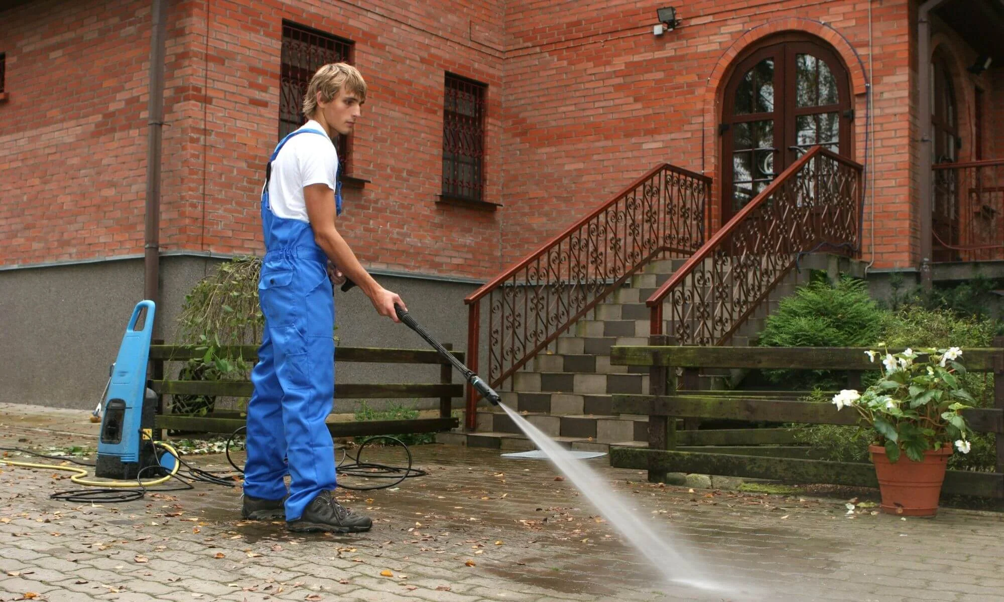 Professional residential pressure washing service cleaning a brick house driveway entrance thoroughly
